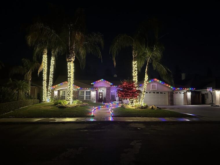 Bakersfield home with wrapped palm trees and multicolor roofline lighting